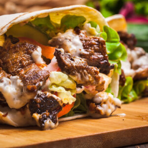 Steak Shawarma Wrap Lunch Box: Tender steak shawarma wrapped in a pita with lettuce, tomato, and garlic sauce.